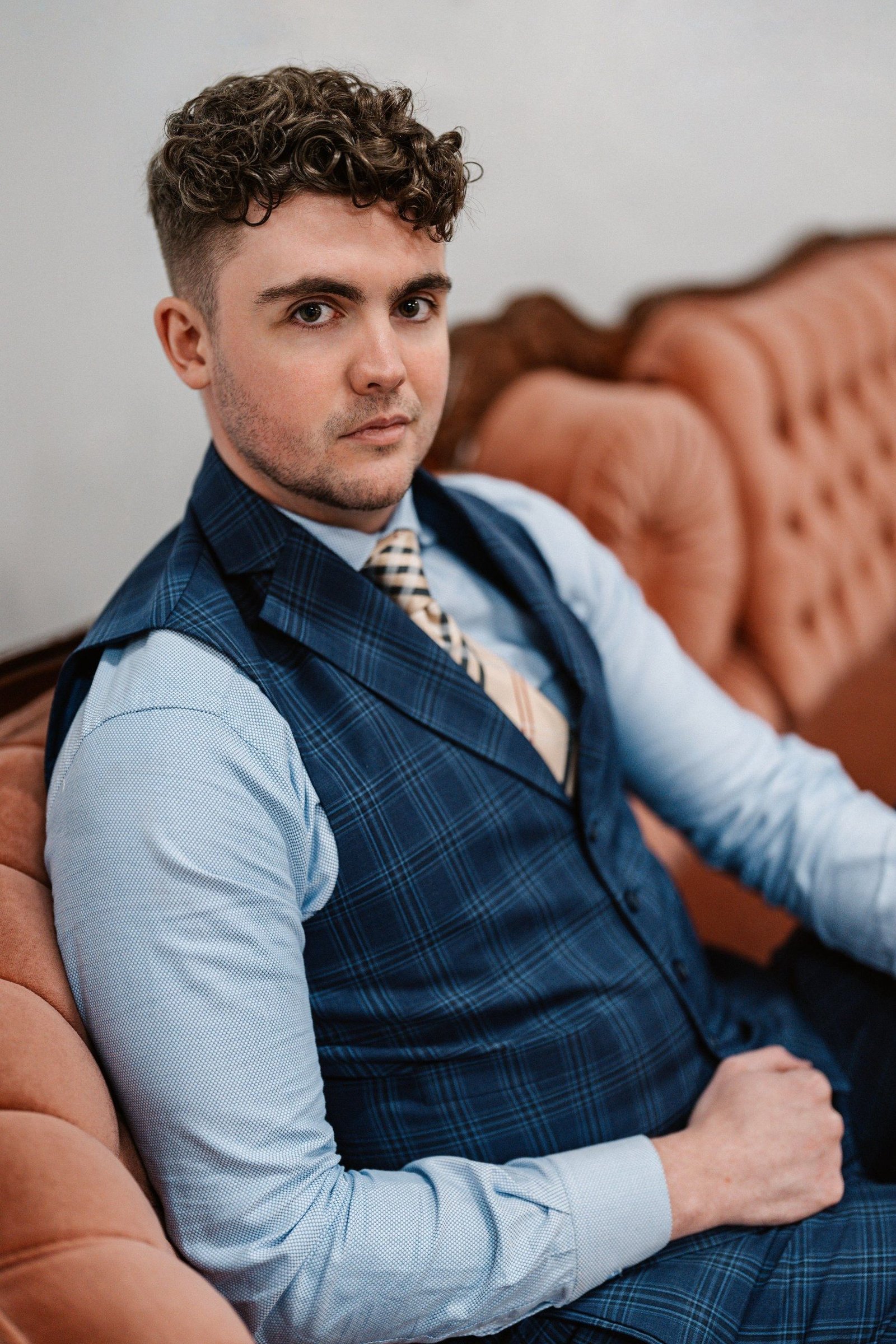 Portrait: seated on a sofa in a navy waistcoat