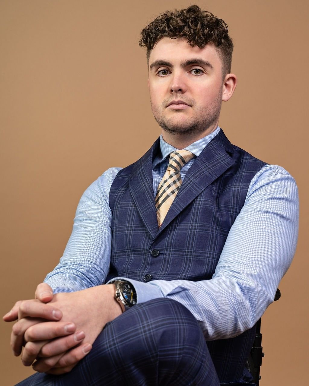 Andrew Kooger seated in a navy waistcoat and tie, looking at the camera