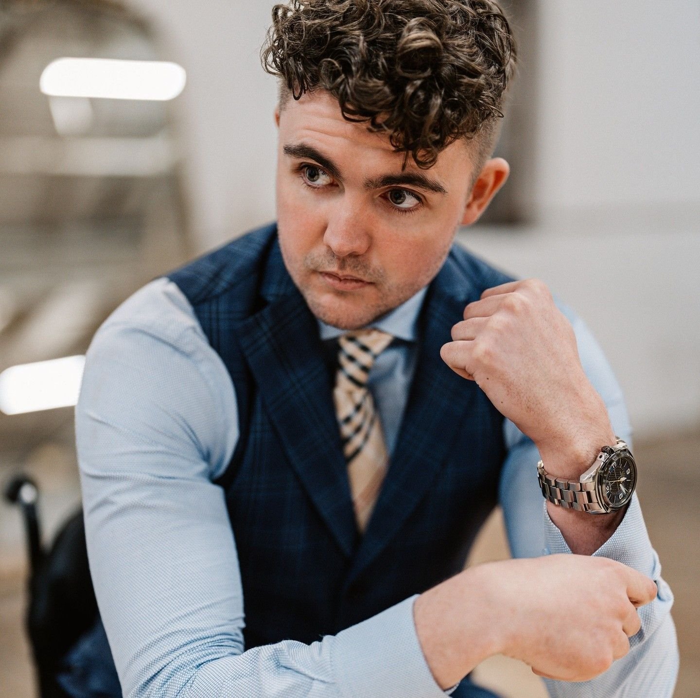 Andrew Kooger in a navy waistcoat, adjusting his watch